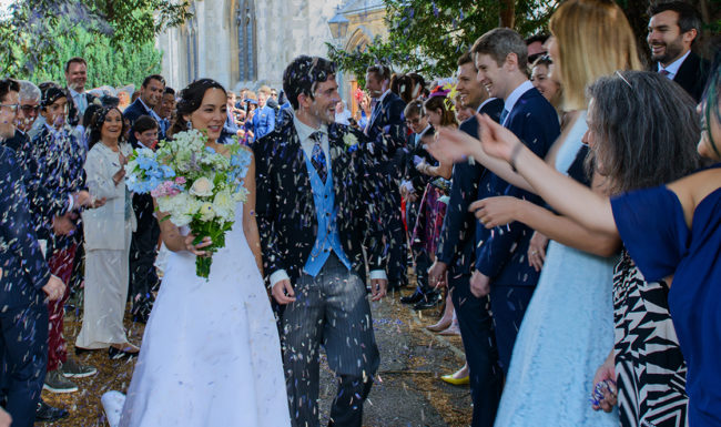 Bride and groom in a churchyard with confetti being thrown