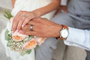 A bride and groom's hands wearing wedding rings