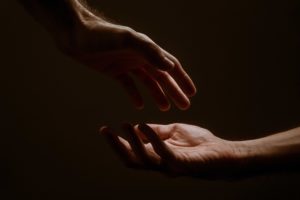 Two hands reaching out to each other in the darkness